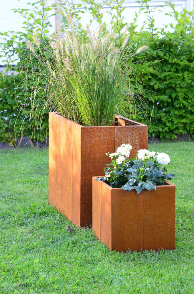 Pflanzkübel Vernazza 40x40x40 cm und Hochbeet aus Cortenstahl in einem grünen Garten