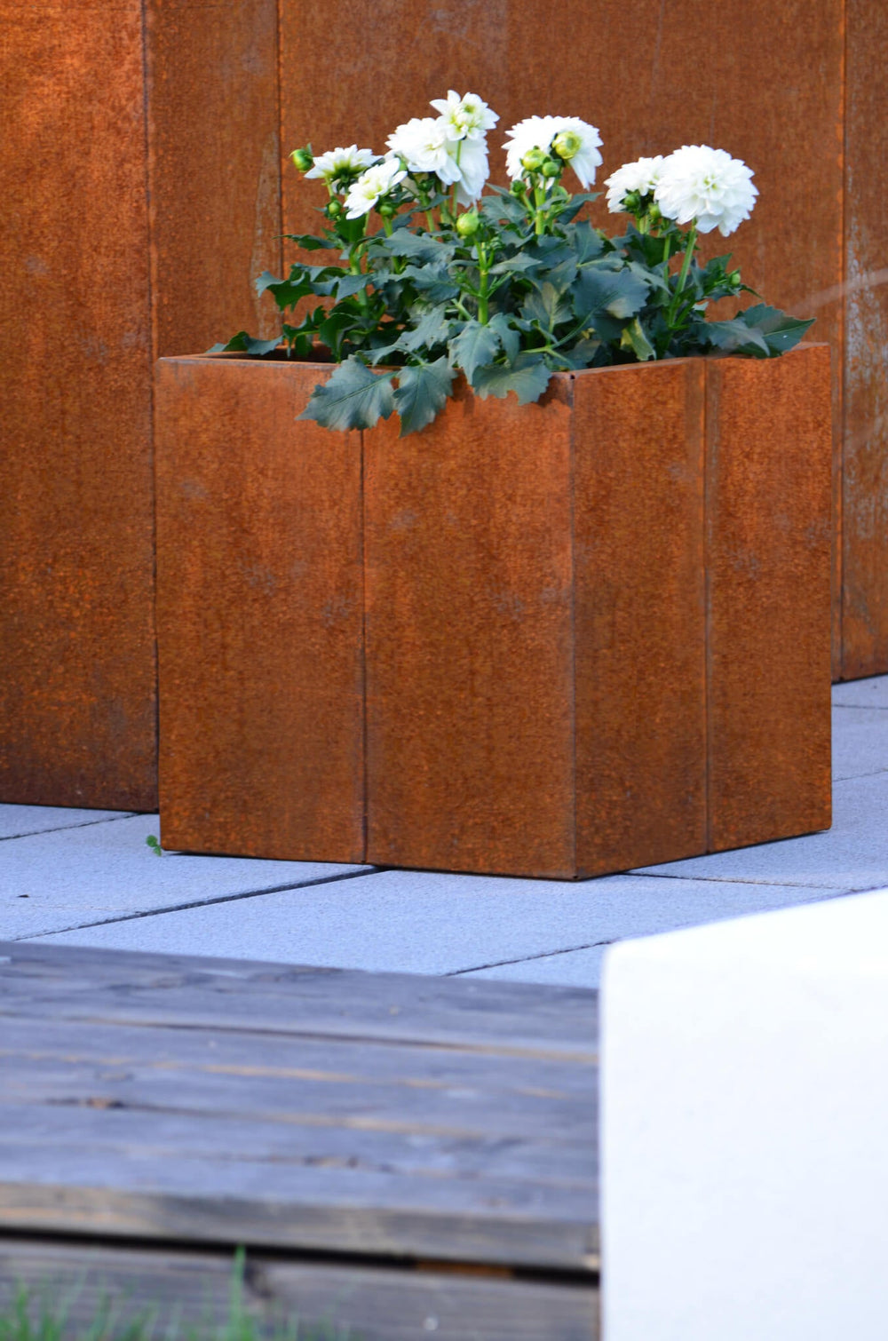 Pflanzkübel Vernazza 40x40x40 cm aus Cortenstahl bepflanzt vor einem Hochbeet aus Cortenstahl